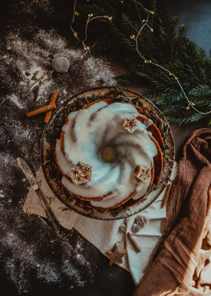 Top view of a delicious festive Bundt cake with icing, surrounded by holiday decorations.