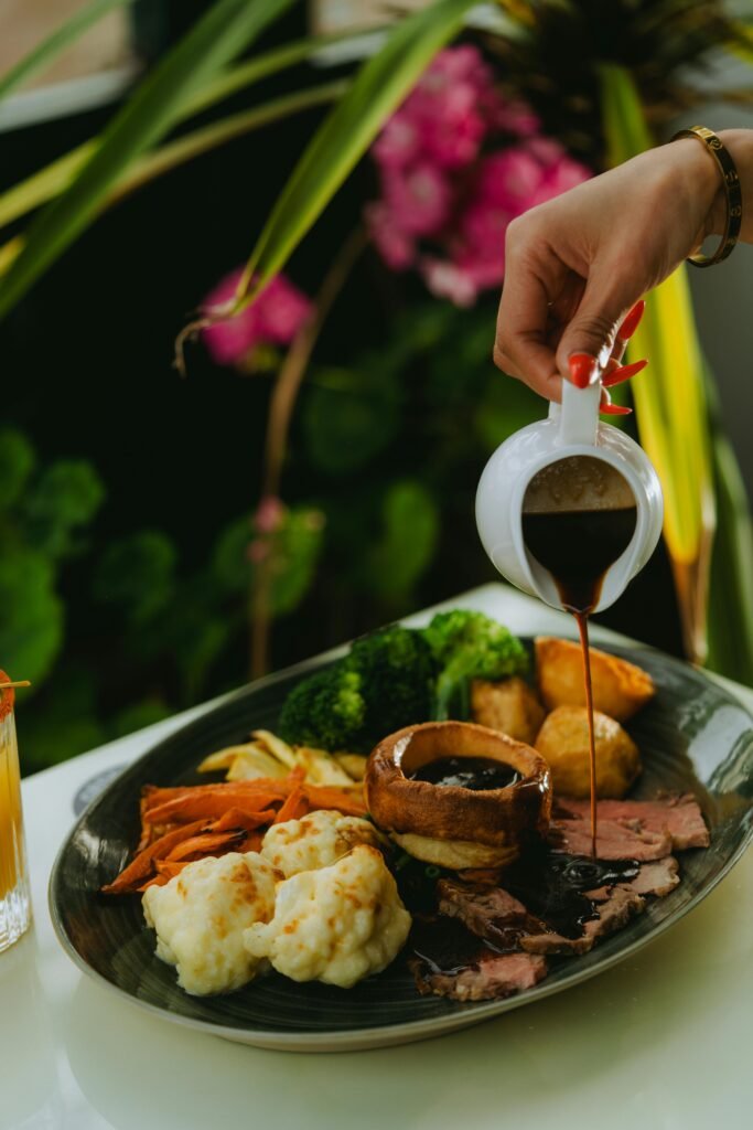Close-up of a roast dinner with vegetables and gravy being poured, perfect for food photography